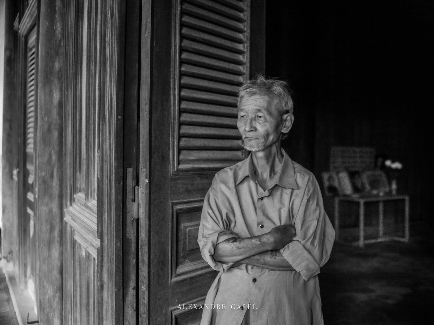 Chân dung một người đàn ông lớn tuổi đứng tựa khung cửa gỗ của ngôi nhà